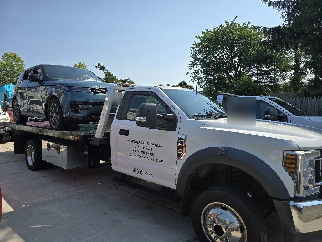 West Hills flatbed tow truck carrying a gray SUV to the shop